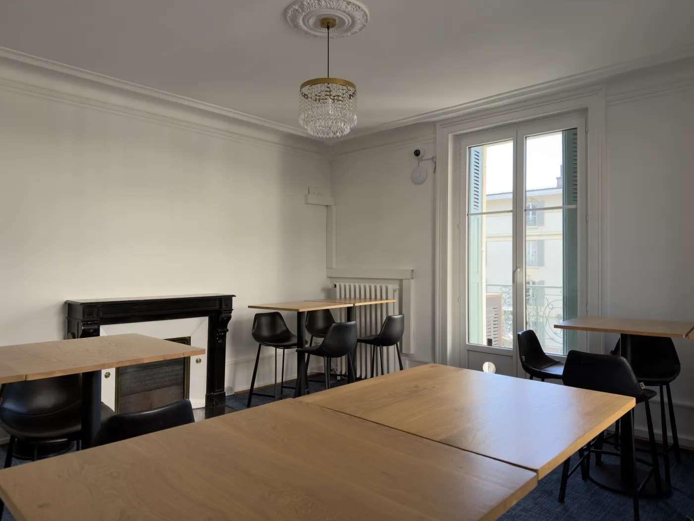 Salle de pause de Yomeeting avec tables, lustre et accès balcon